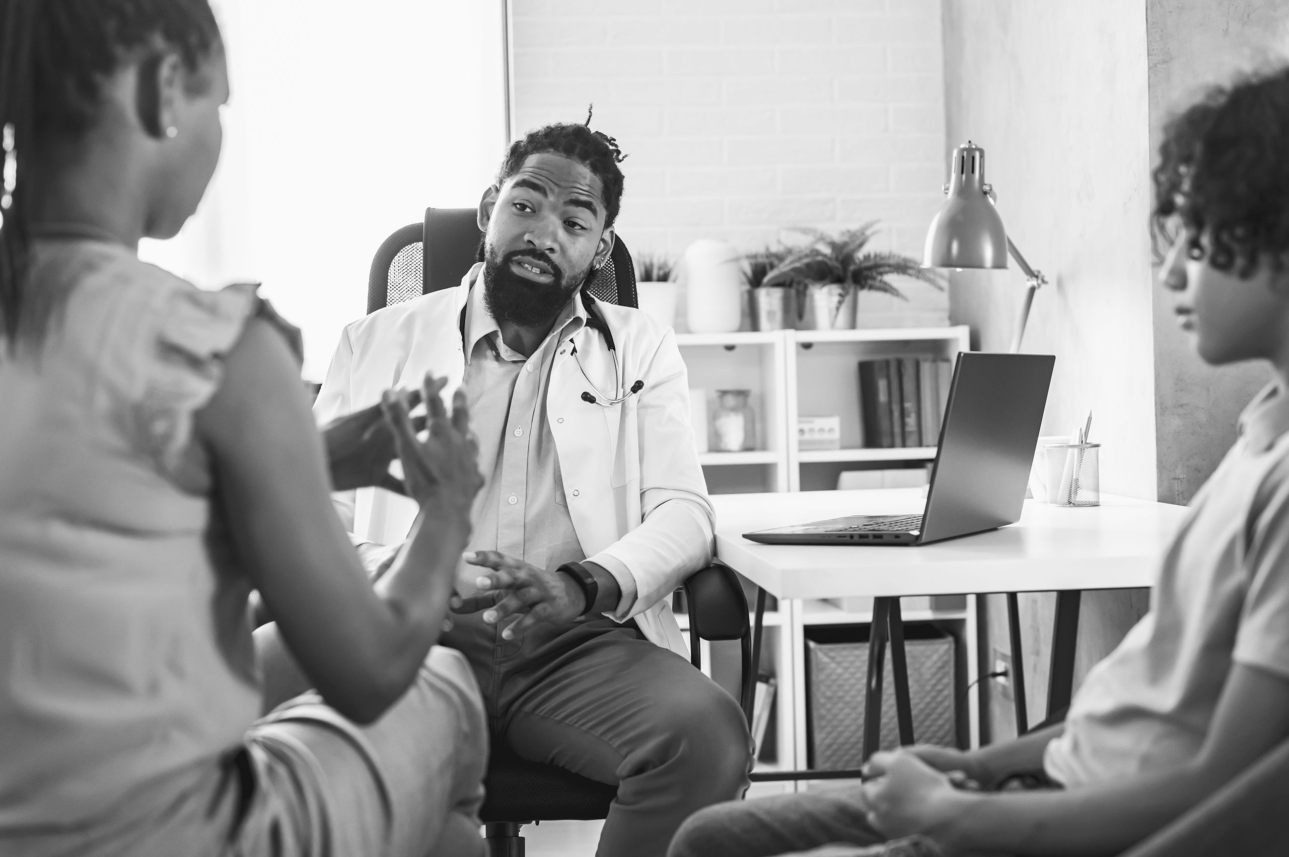 An image of a doctor talking with a mother and her teenage son.
