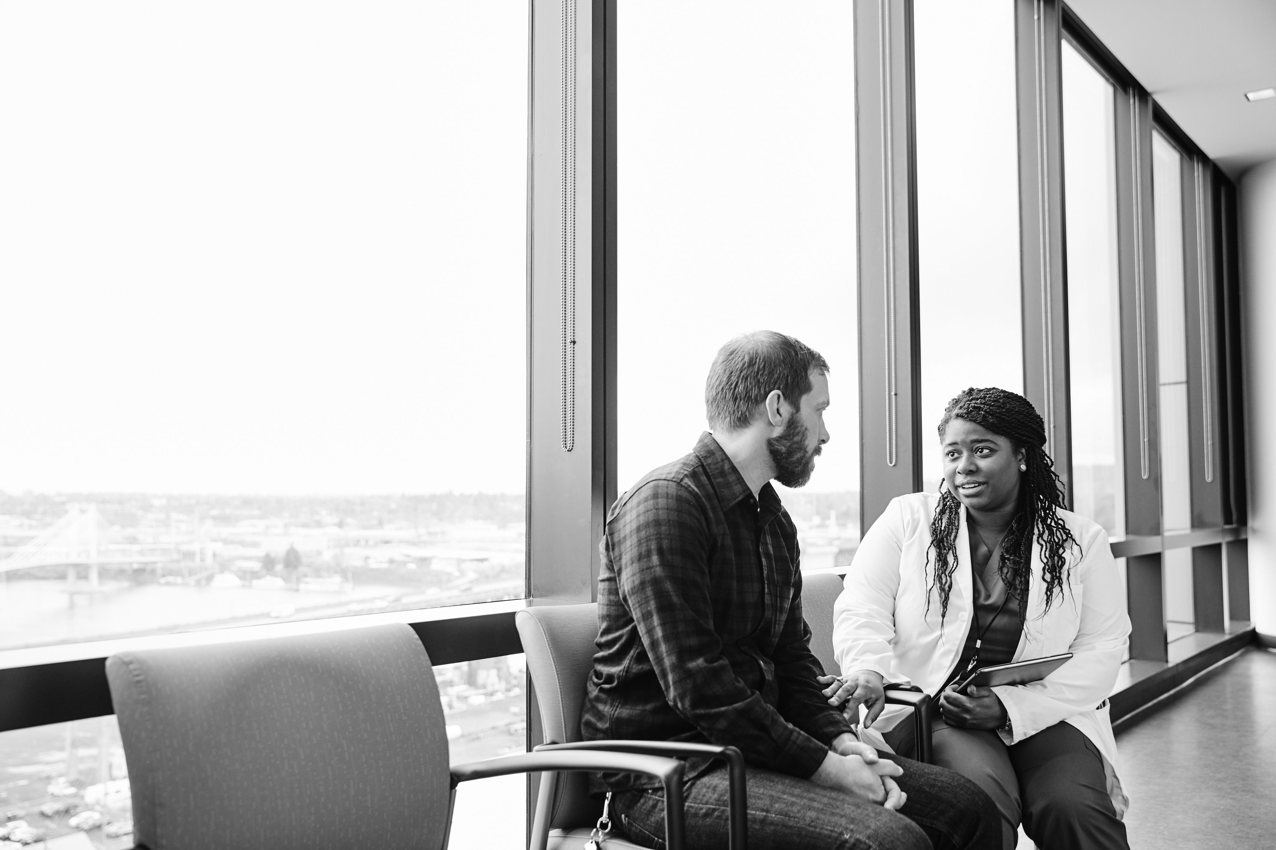 Black and white image of a doctor and patient discussing results.