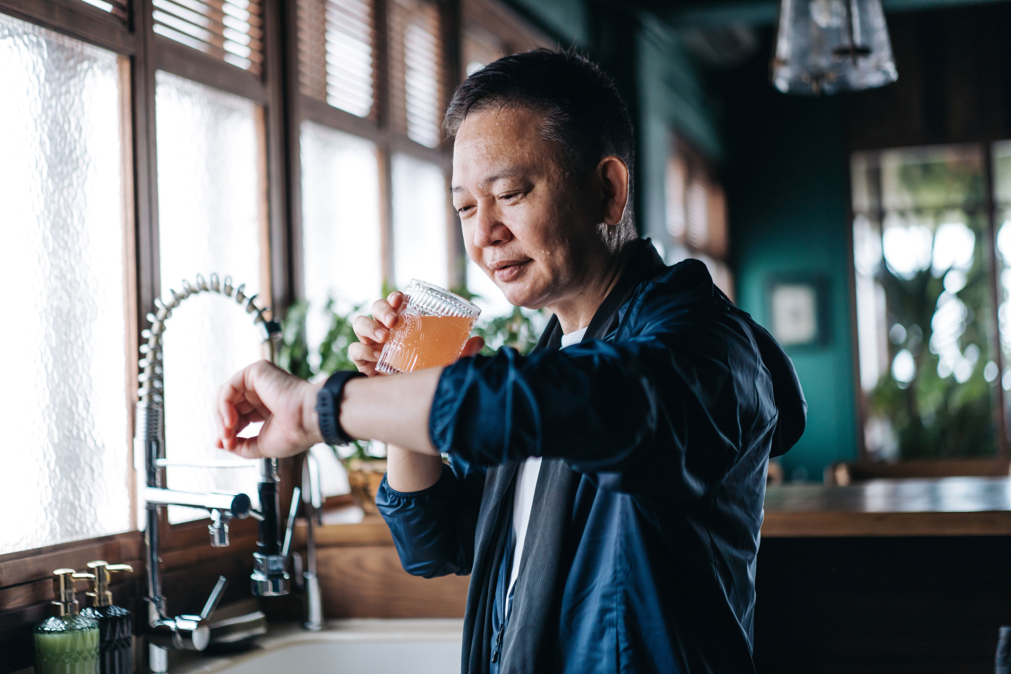 Image of a man in his kitchen drinking a beverage.
